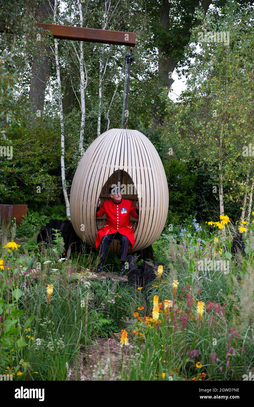 A Chelsea Pensioner relaxes in the Yeo Valley show garden at the RHS Chelsea Flower Show. Stock Photo