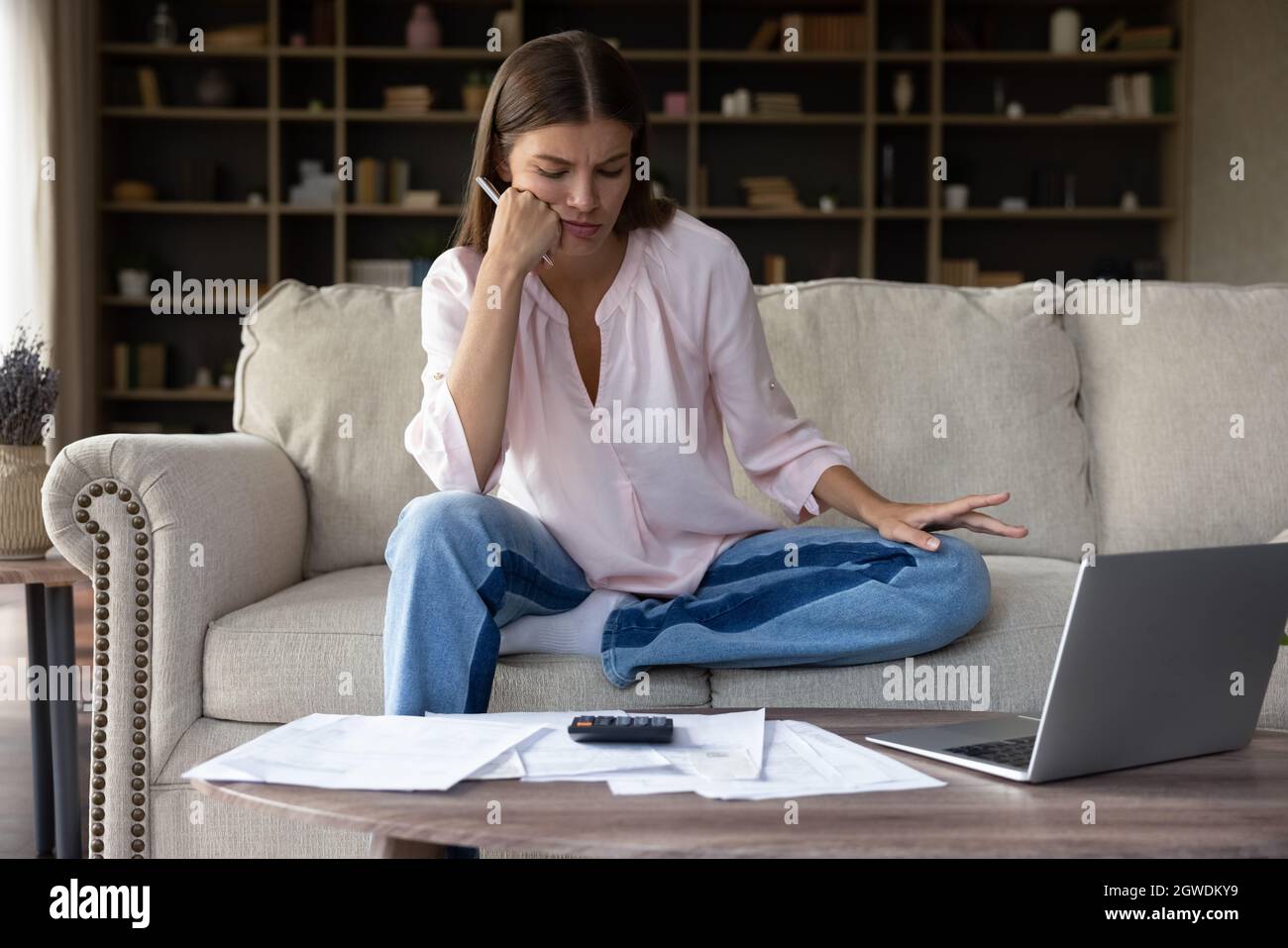 Concerned frustrated millennial homeowner girl looking at bills for payments Stock Photo