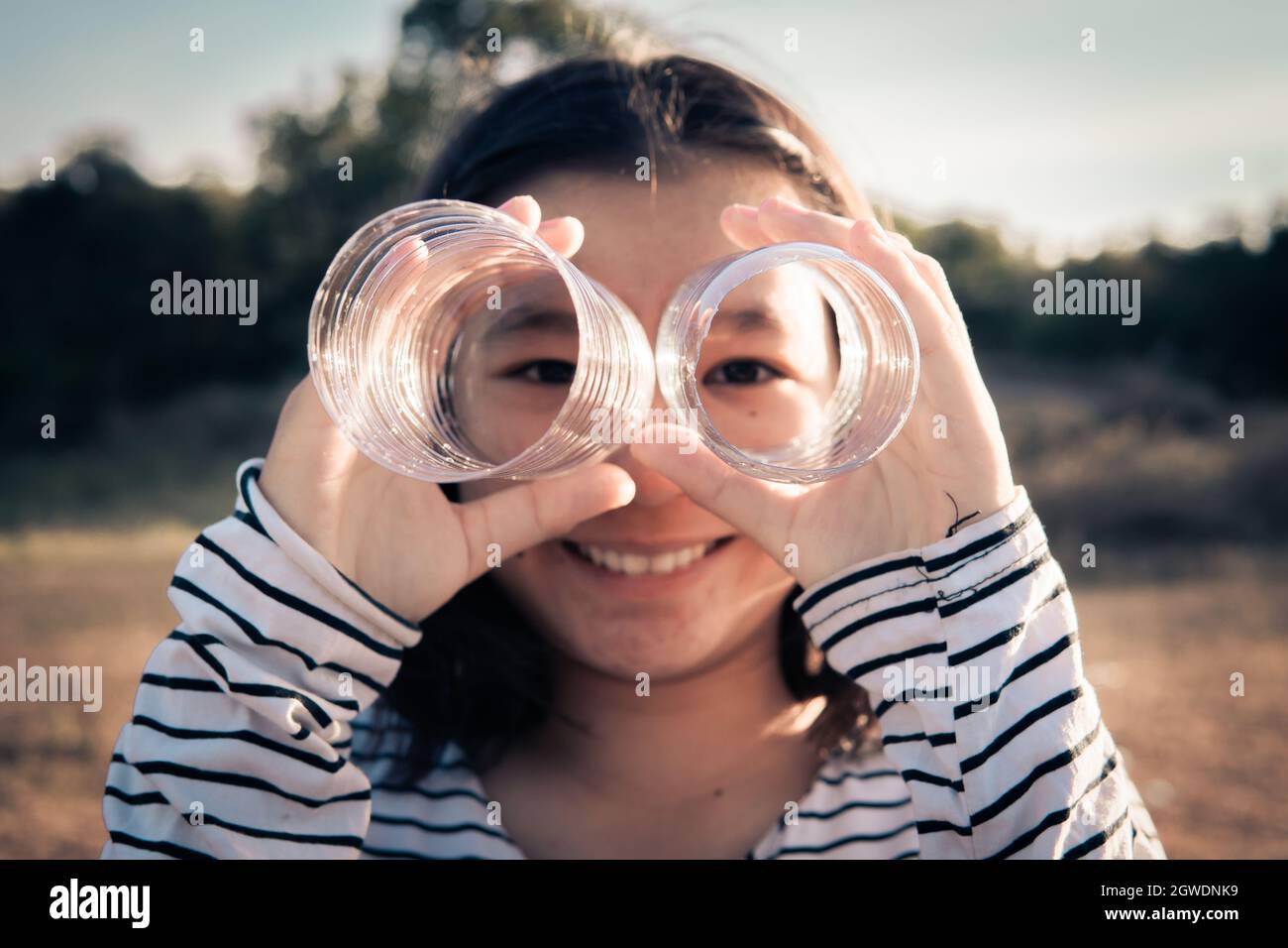 Portrait Of Smiling Girl Looking Through Hole In Plastic Stock Photo