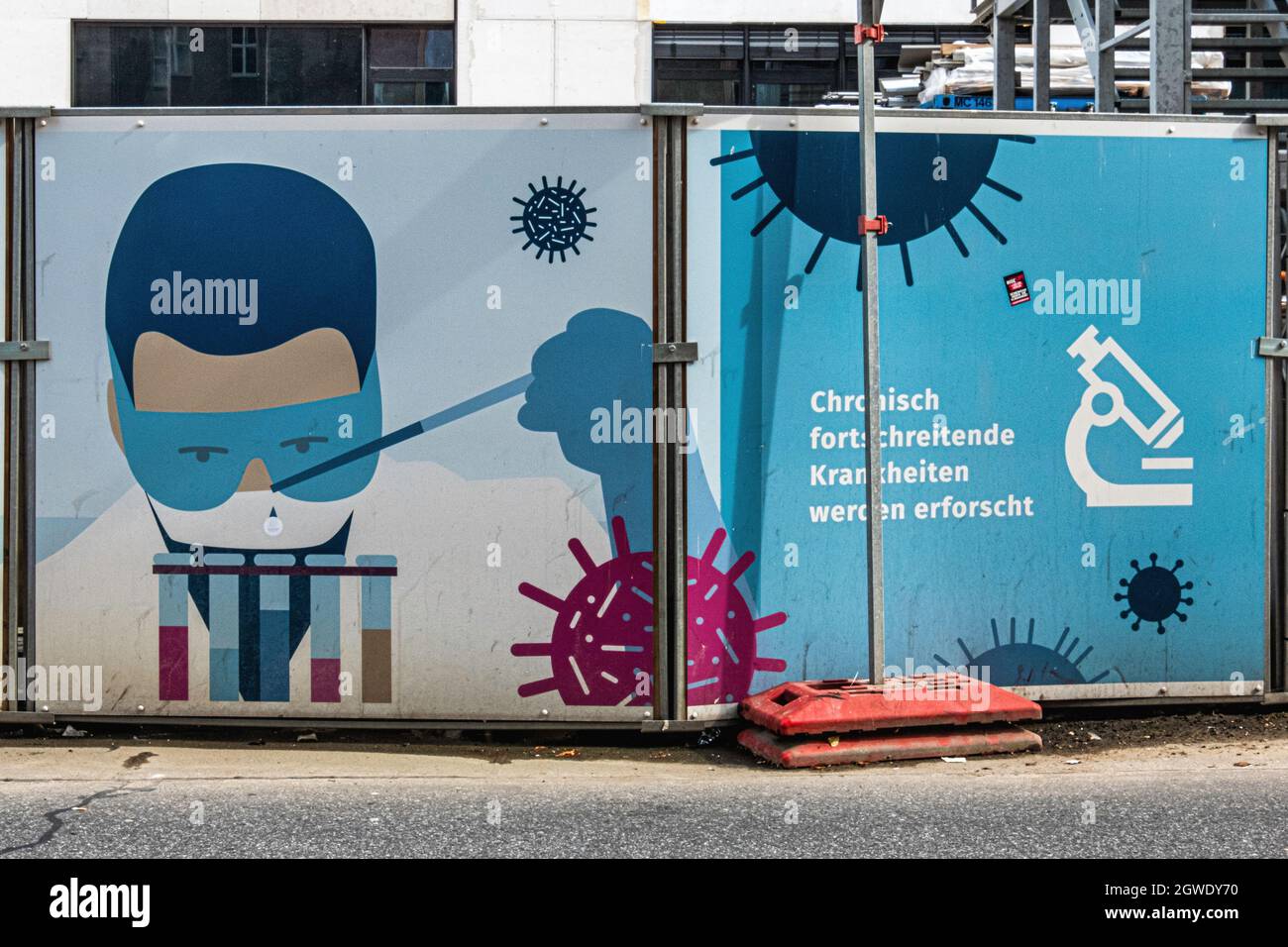 Hoarding around building site. Scientist or doctor with test tubes and virus in Luisenstrasse, Mitte,Berlin Stock Photo