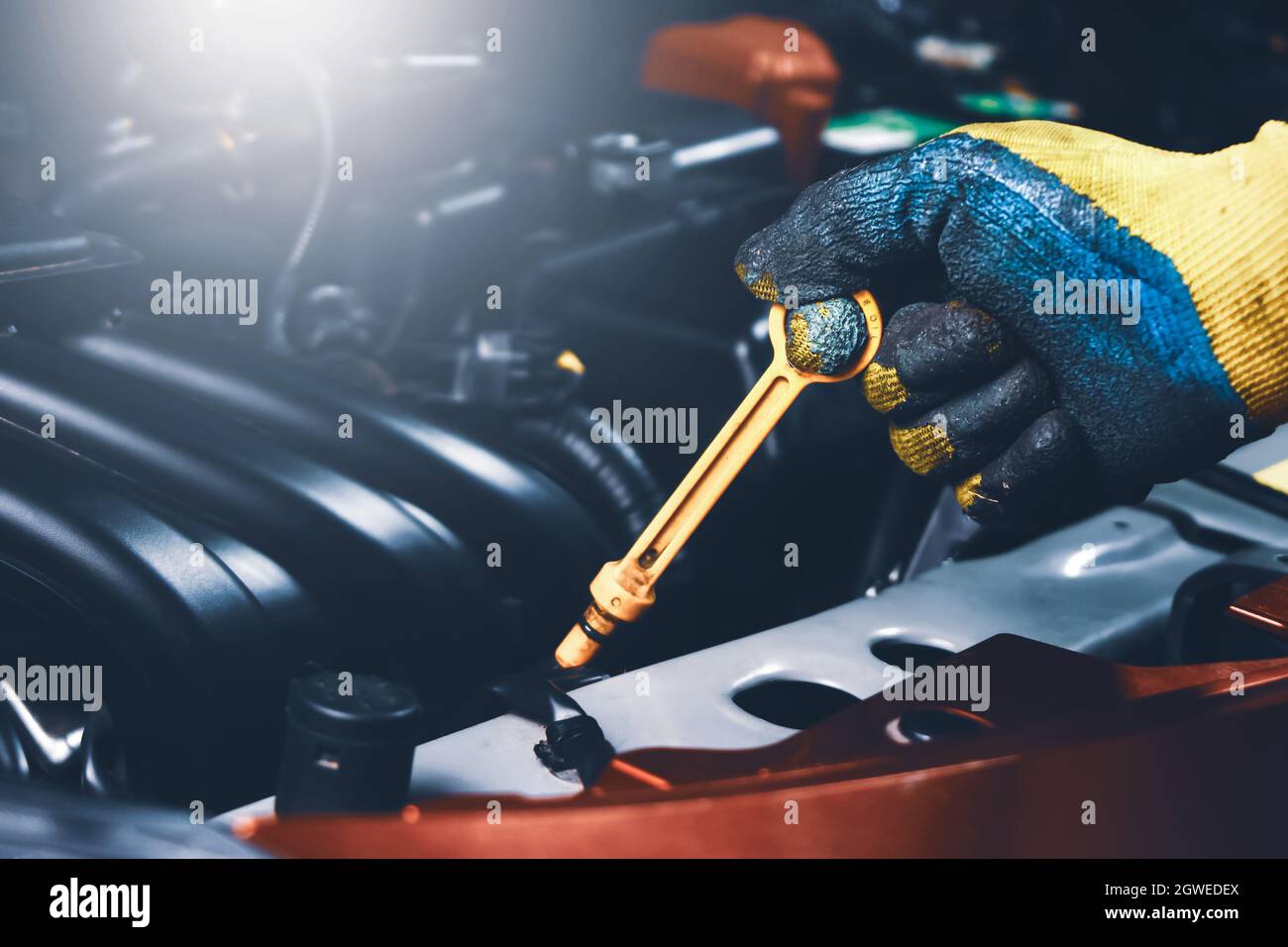 Mechanic hand pulling up oil dipstick of the car engine for checking