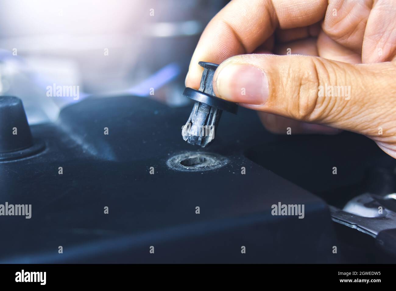 Mechanic hand installing automotive plastic fasteners to the car body