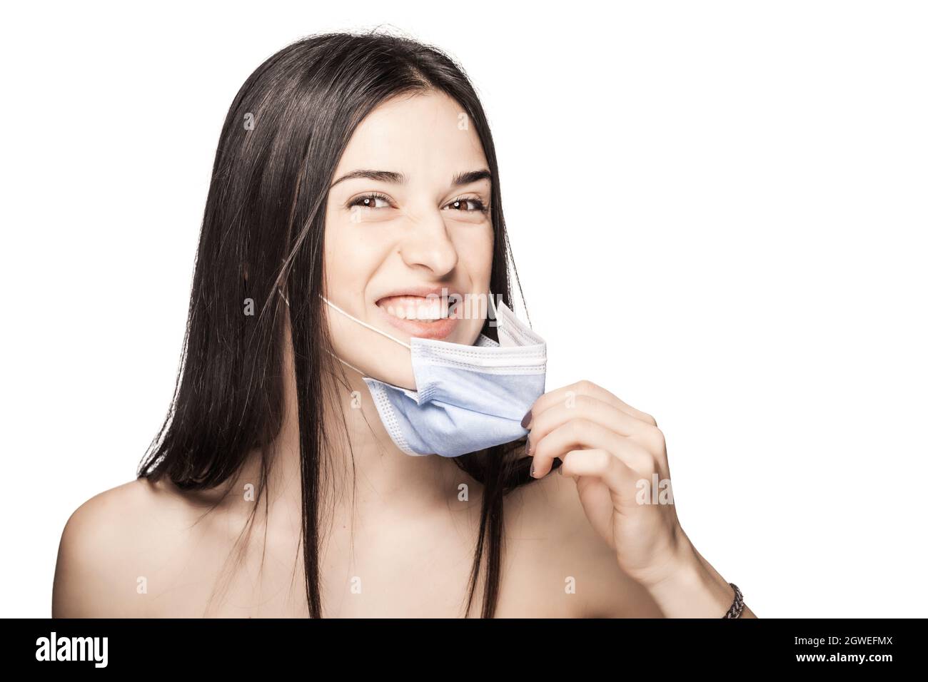 Angry girl pulling away medical face mask. Portrait against white background. Stock Photo