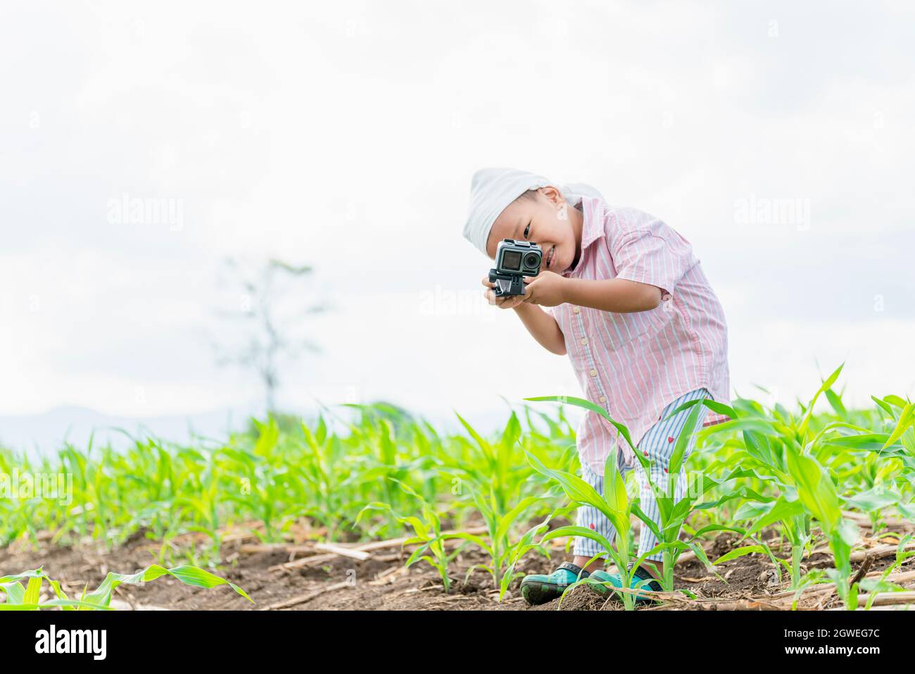 Boy With Camera Standing On Field Against Sky Stock Photo