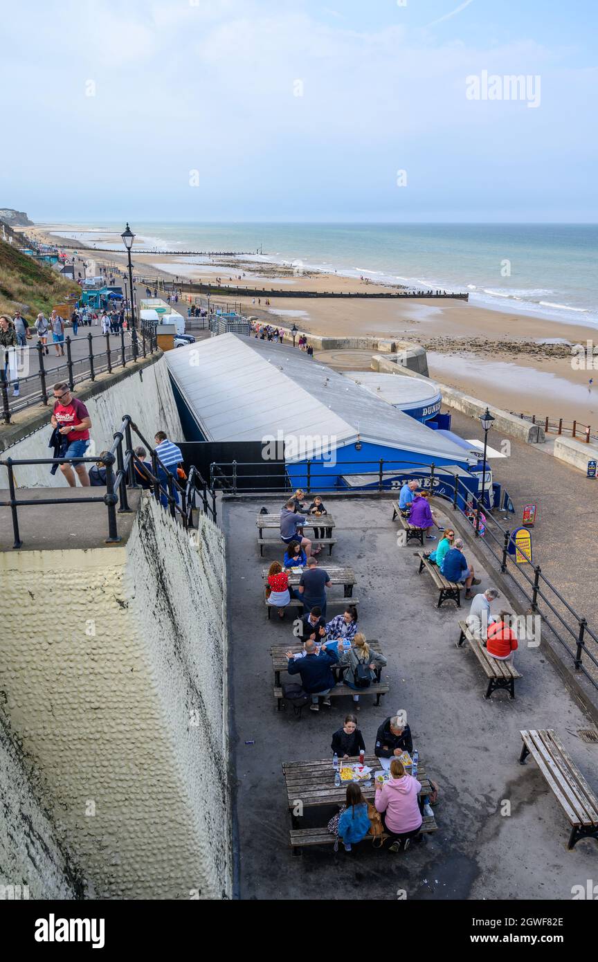 People sitting outside eating and drinking overlooking Cromer beach, Norfolk, England. Stock Photo