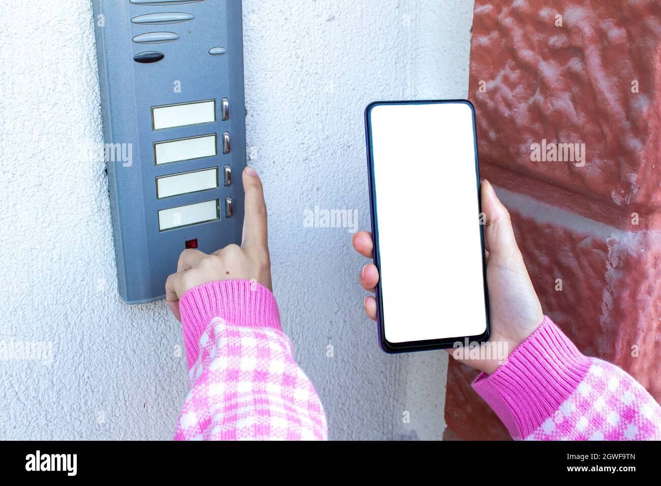 Woman rings doorbell and holding mobile phone with blank white desktop