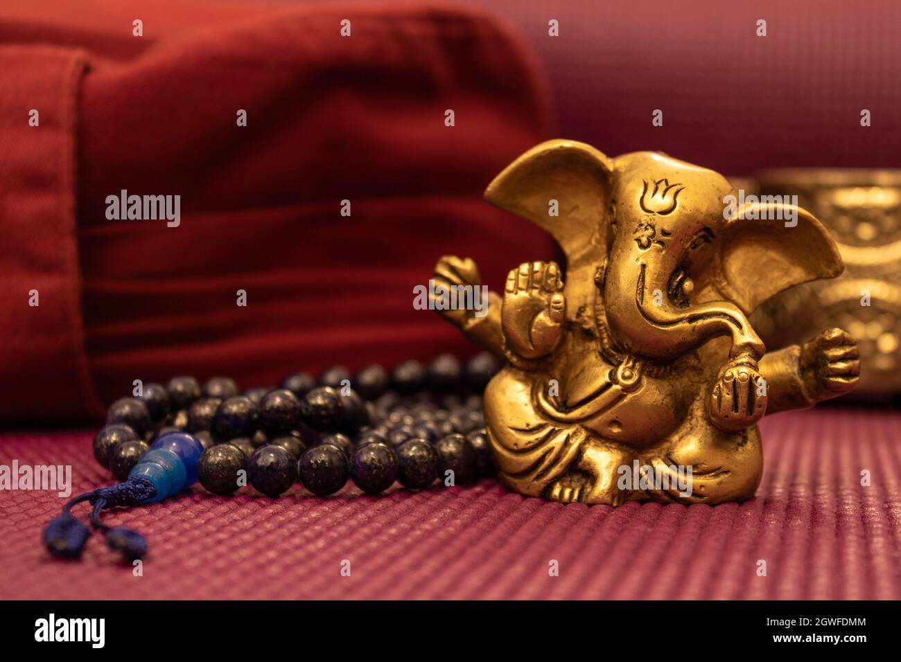 Close Up Of Golden Statue Of Ganesha On Yoga Mat With Blue Prayer Beads And  Yoga Pillow Stock Photo - Alamy
