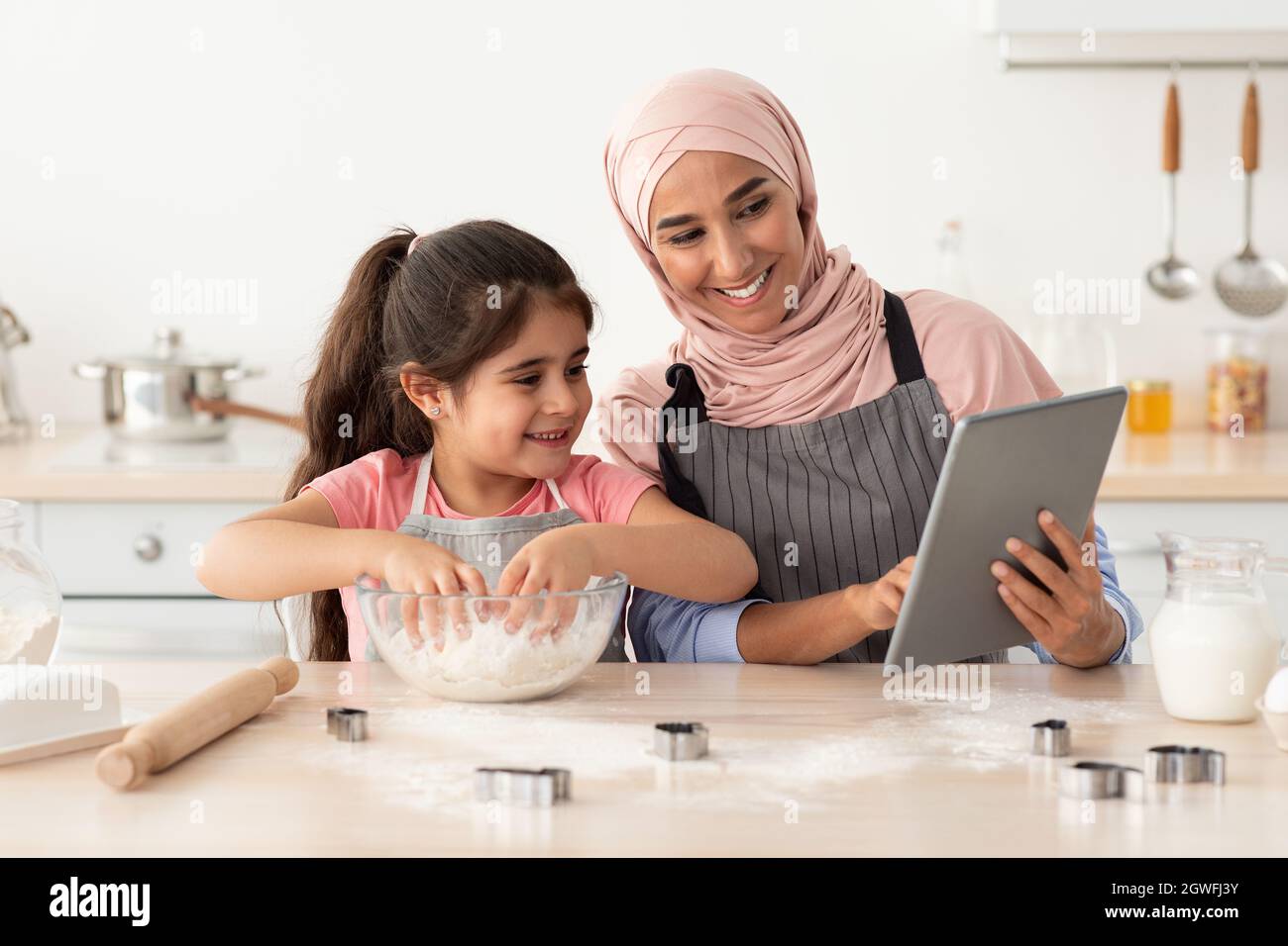 Muslim Mother Baking With Little Daughter At Home Checking Cookies Recipe Online On Digital Tablet Happy Islamic Mom In Hijab Enjoying Cooking Homem Stock Photo Alamy