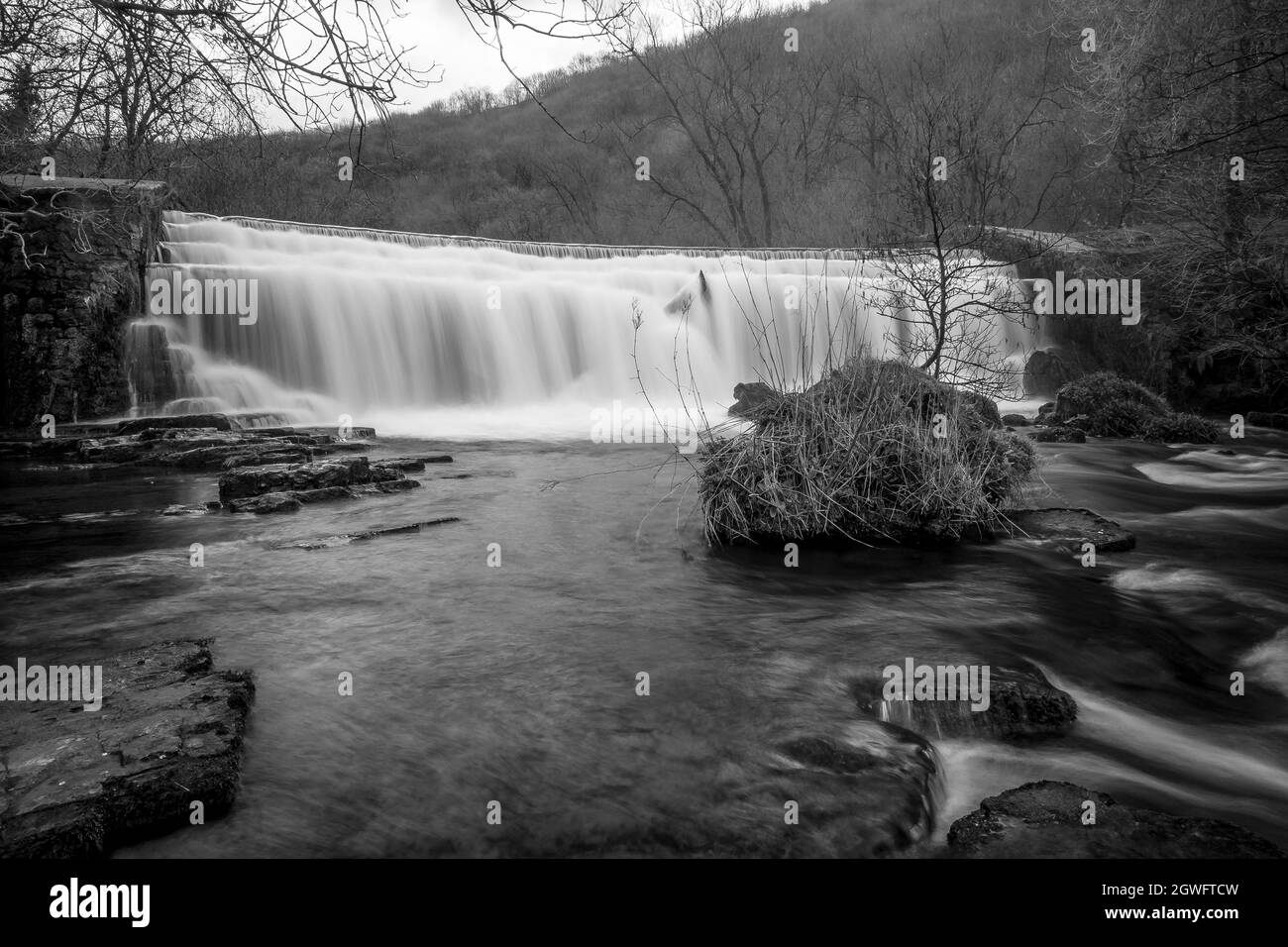 Long black and white exposure of the Monsal Dale Weir waterfall and River Wye on the Monsal Trail in the Peak District Stock Photo