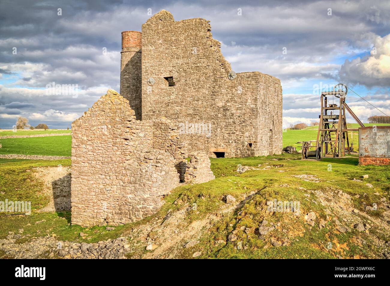 The Cornish engine house, circular chimney and pit-head winding gear at Magpie Mine, Sheldon, a preserved lead mine in the Peak District National Park Stock Photo