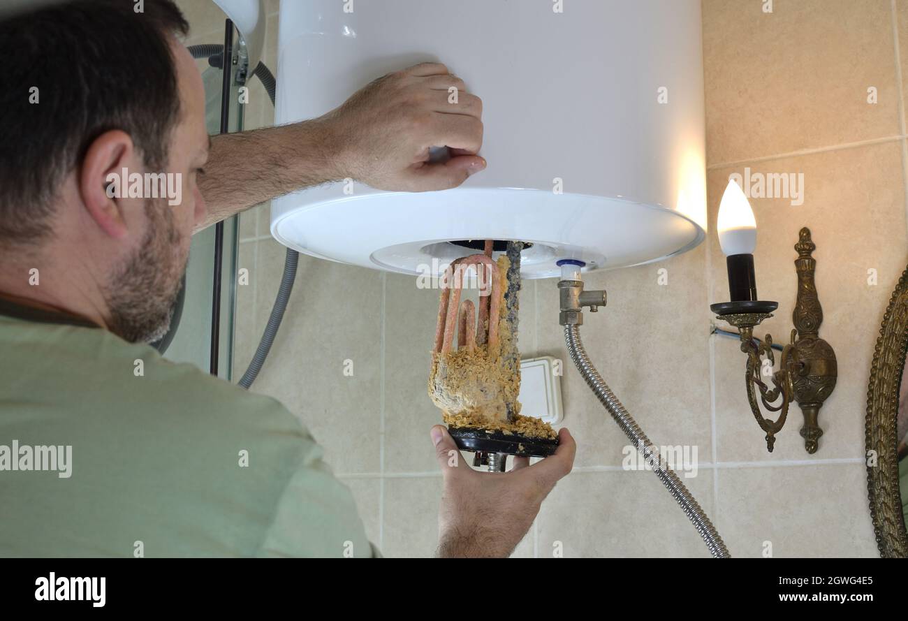 Man Taking Out An Old Water Heater With Scale Deposition From A Boiler