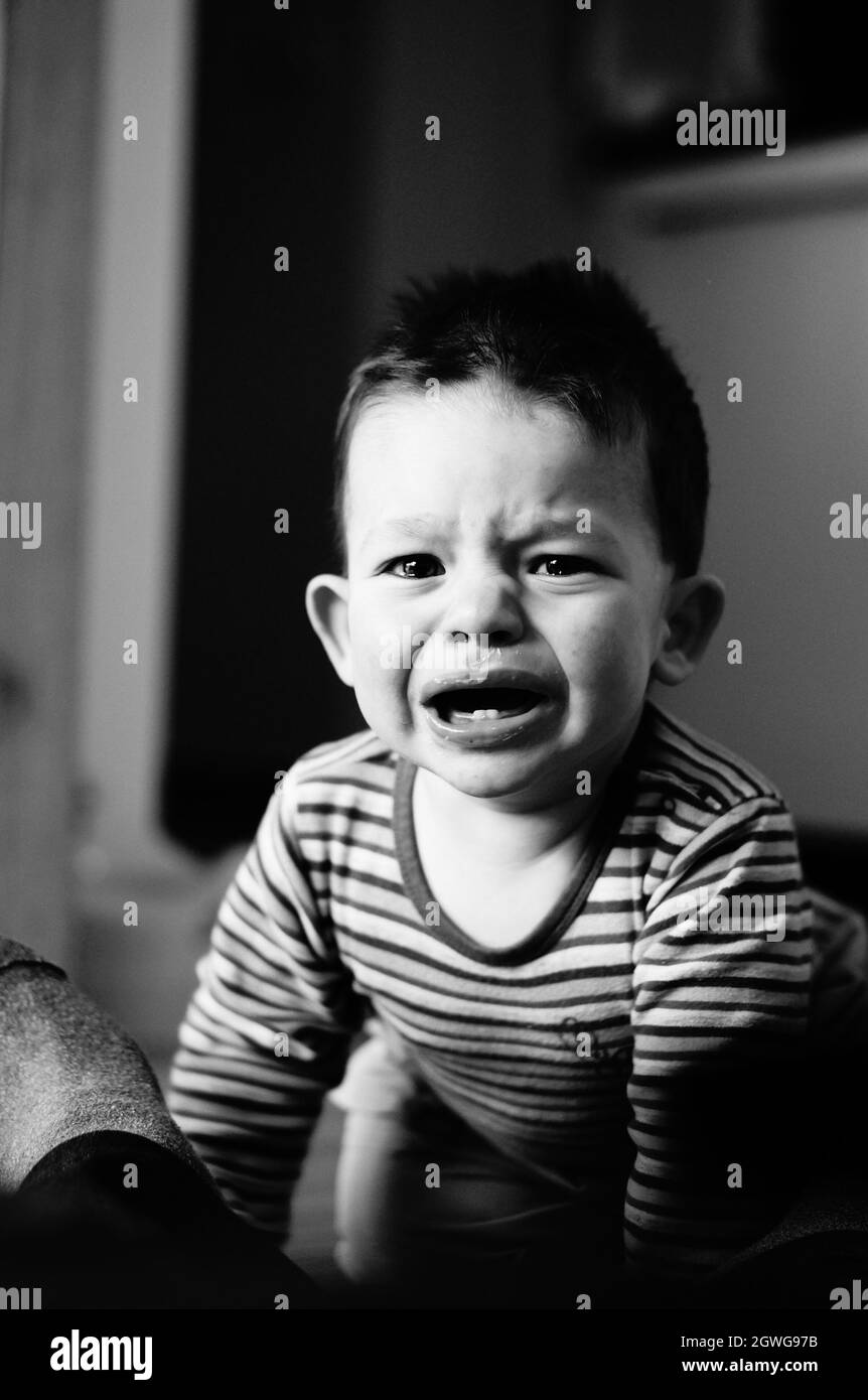 A greyscale portrait of a Caucasian little crying boy Stock Photo