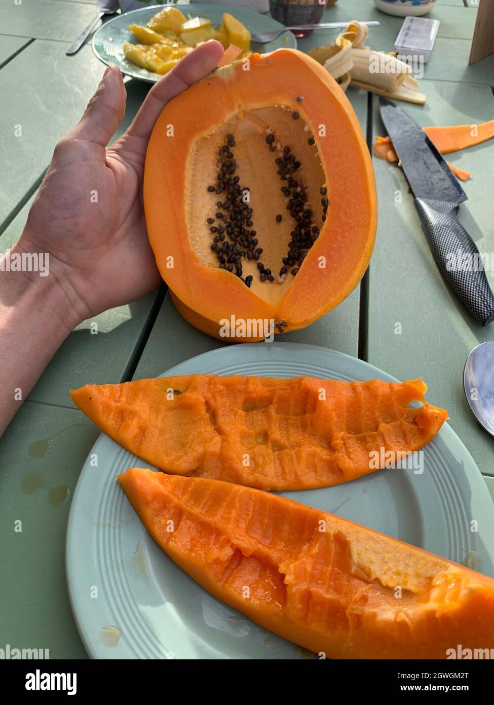 Close-up Of Hand Holding Papaya Fruit In Plate On Table Stock Photo