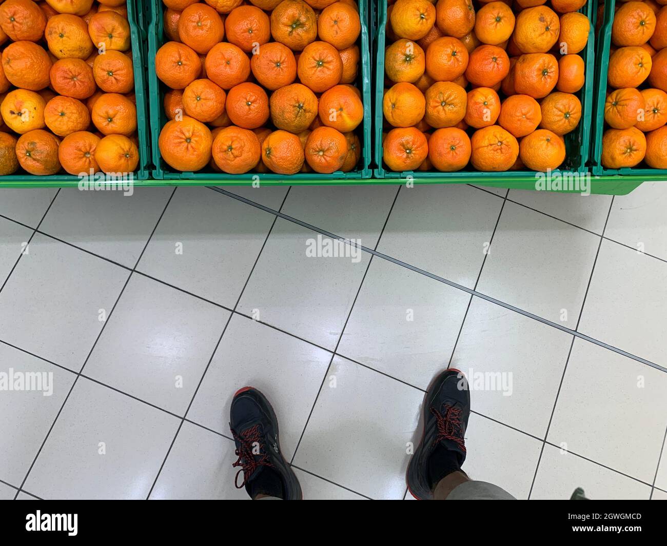 Low Section Of Person Standing In Front Of Oranges For Sale At Market Stock Photo
