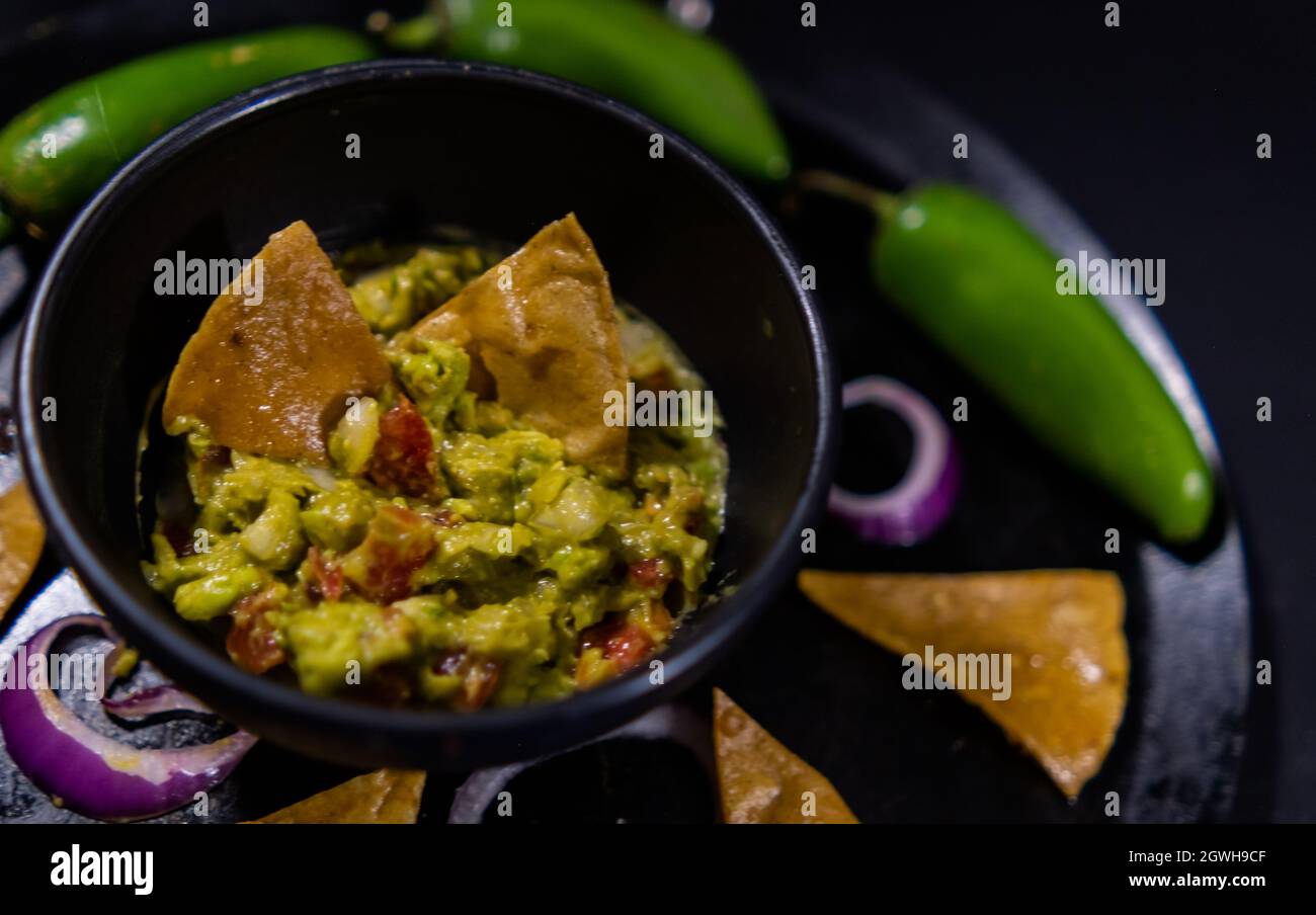Bowl of guacamole on Mexican comal decorated with tortilla chips