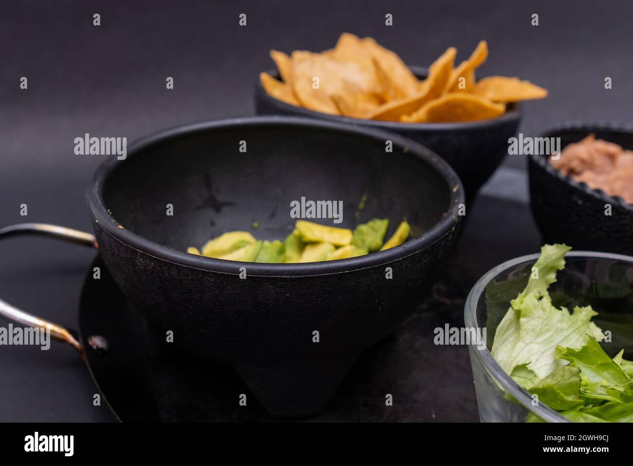 https://c8.alamy.com/comp/2GWH9CJ/bowls-of-tortilla-chips-refried-beans-and-chopped-lettuce-on-mexican-comal-2GWH9CJ.jpg