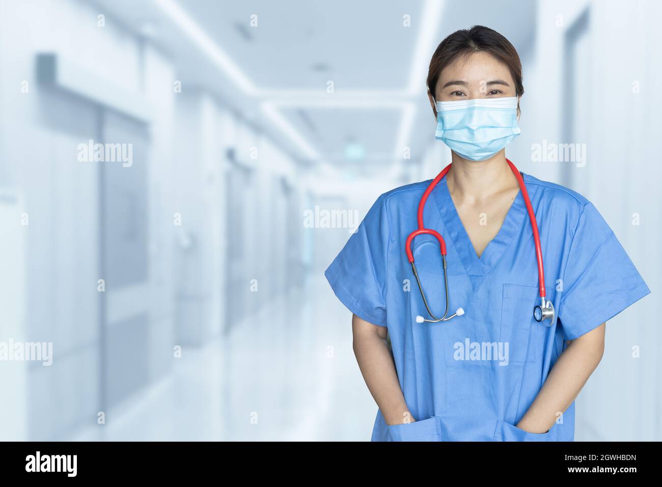 Portrait Asian Doctor or Nurse with mask standing in blur hospital  background copy space Stock Photo - Alamy