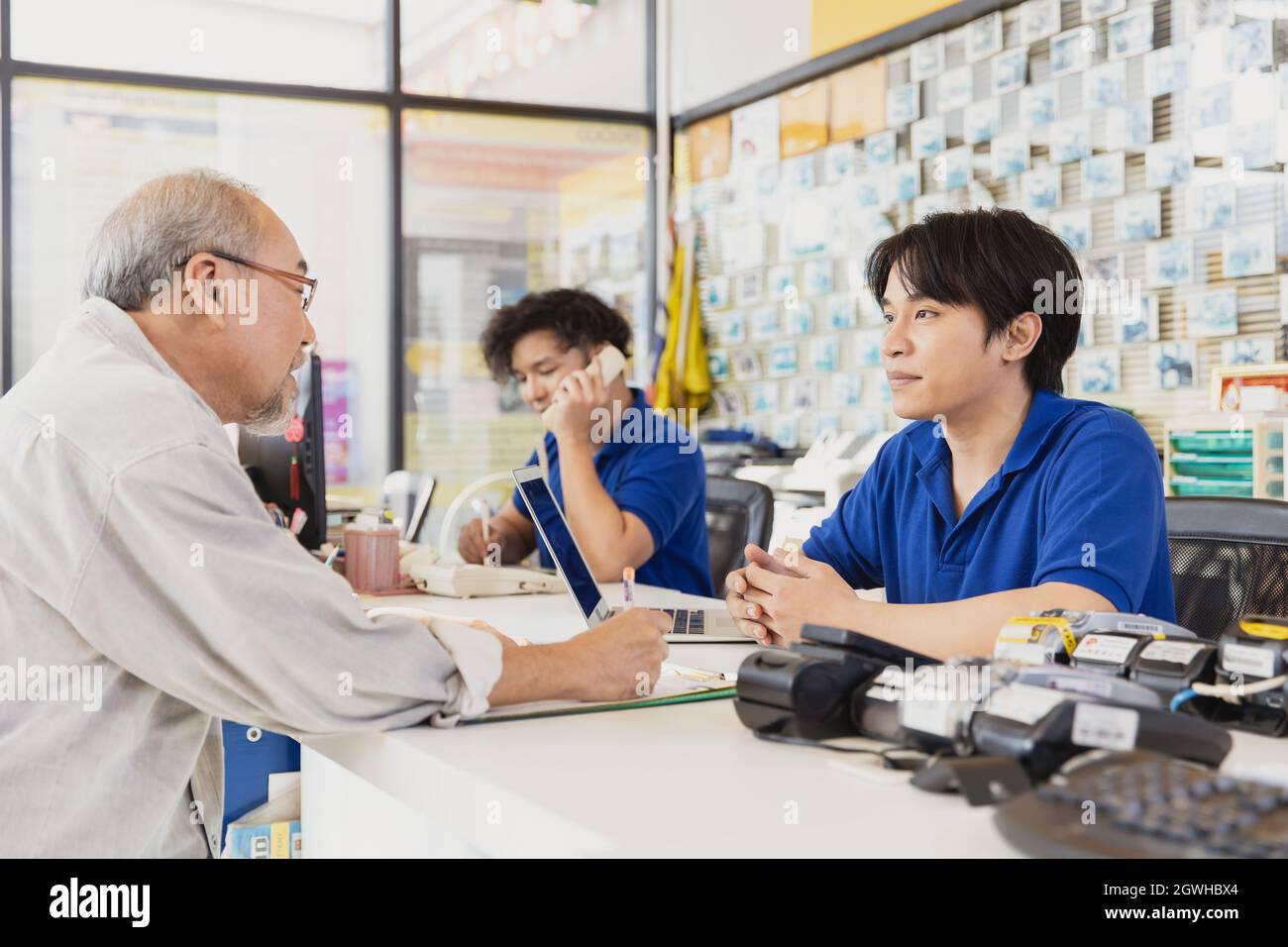 Customer sign contract document to apply membership and talk to reception male staff at counter service in business shop. Stock Photo