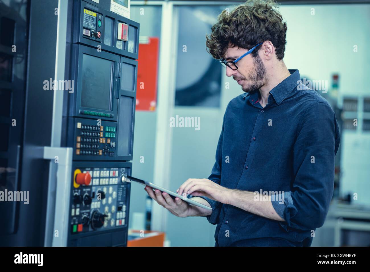 Young Engineer American professional staff worker operate advance machine with tablet computer. Stock Photo
