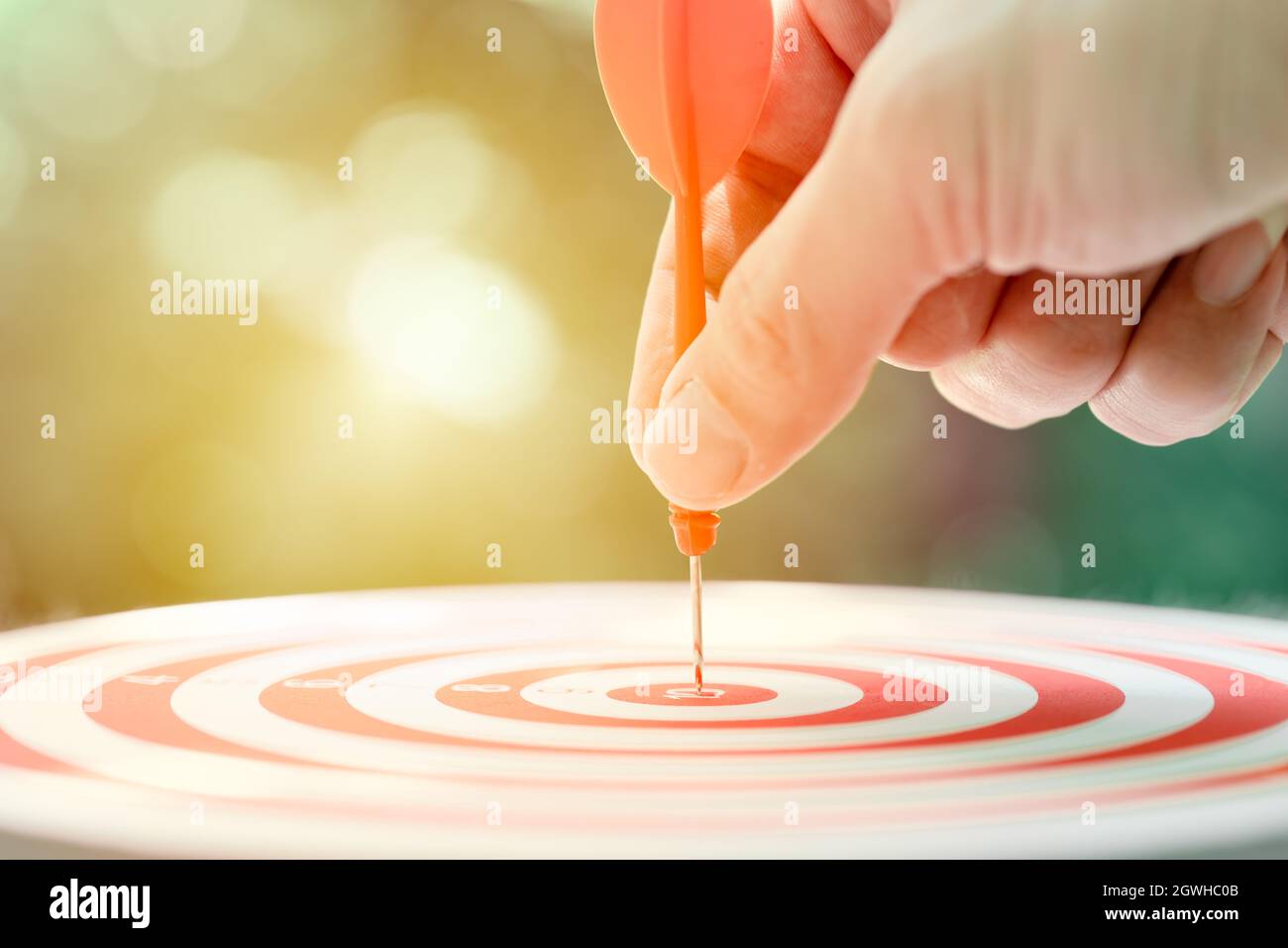 Business target concept, male hand holding arrow dart at center