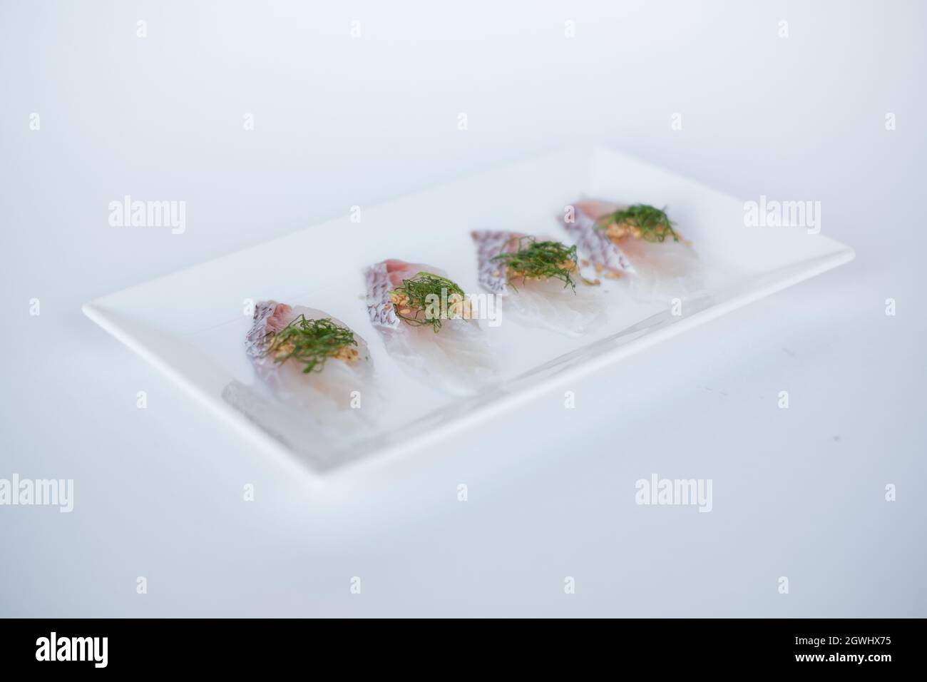 Sea bass sashimi on white plate on white background. Isolated on white