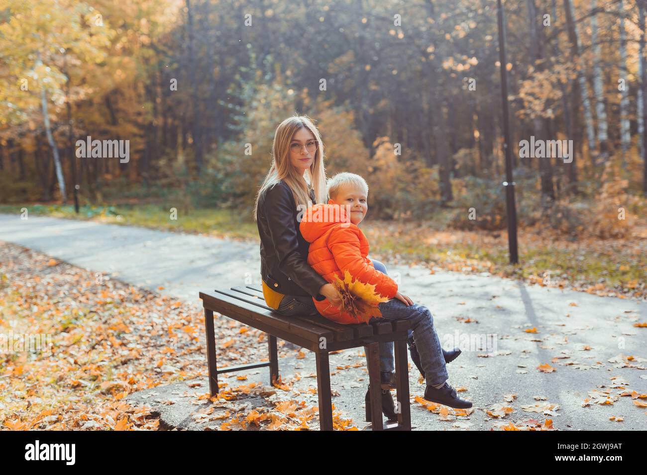 Single parent mother and child boy in the autumn in park sit on bench ...