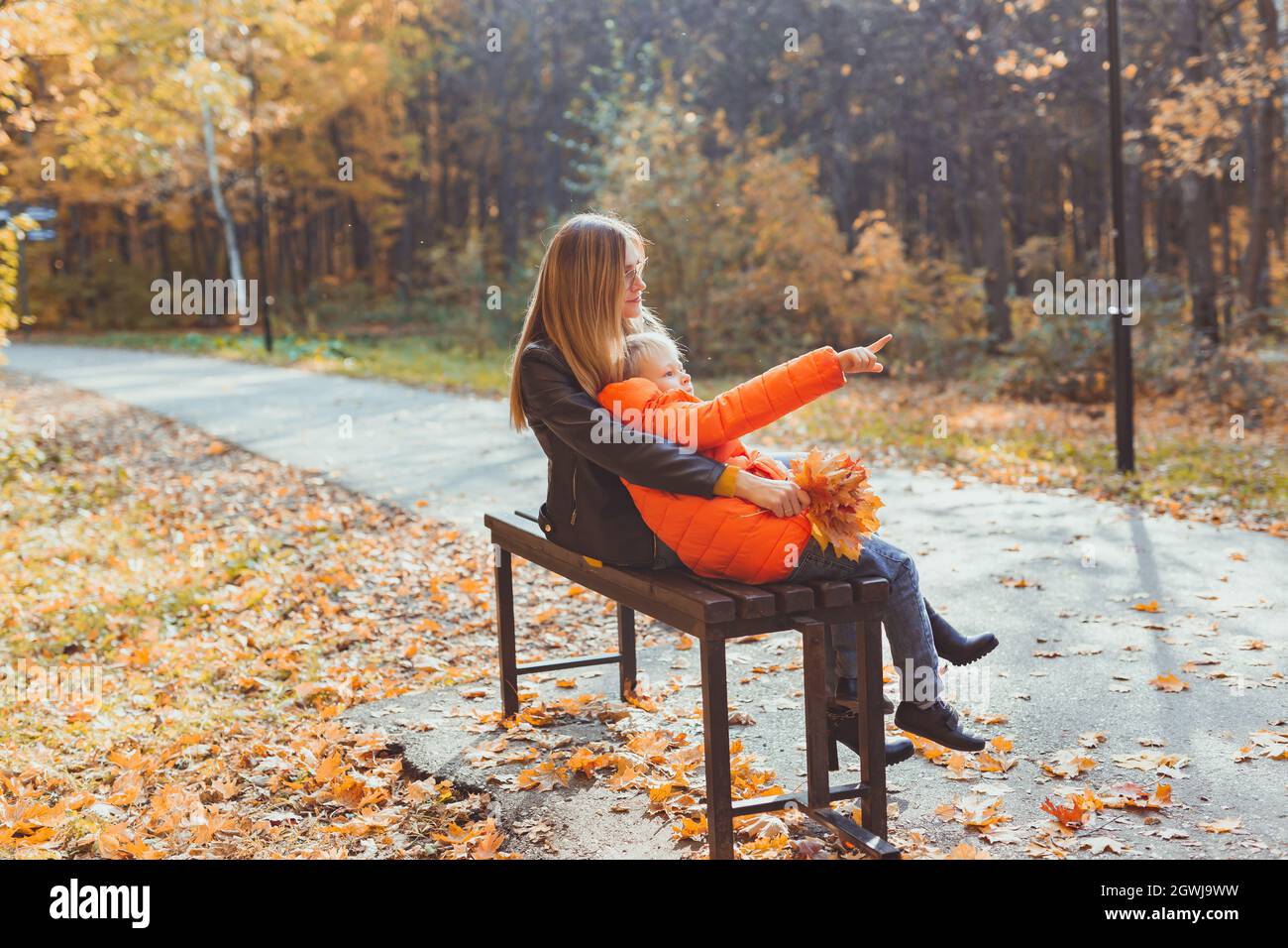 Single parent mother and child boy in the autumn in park sit on bench ...