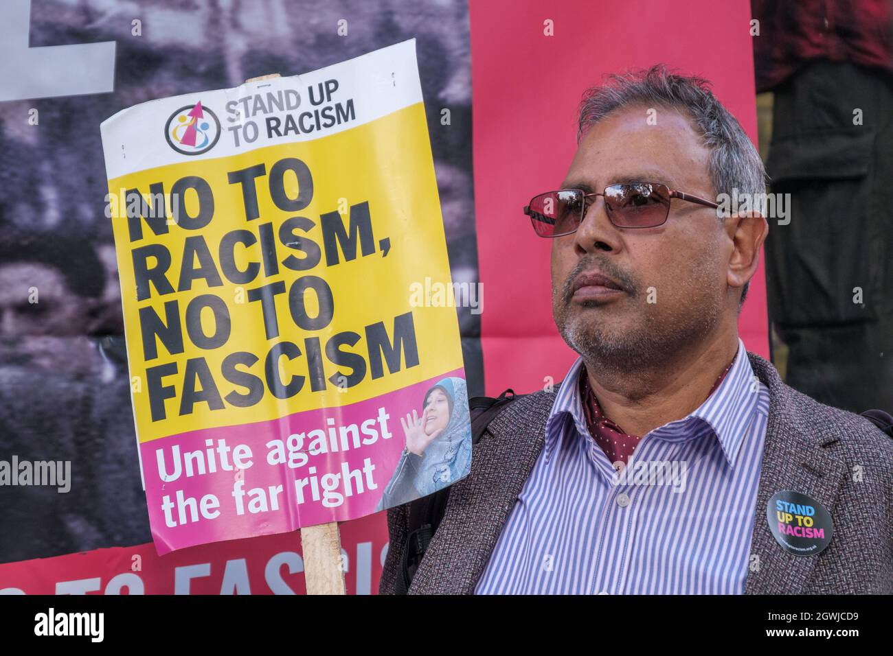 London, UK. 3rd Oct 2021. A man holds a placard against racism and fascism at the rally on the 85th anniversary of the Battle of Cable St to remember the act of unity against the fascist threat when the Jewish and Irish communities of East London and their allies blocked the streets to prevent Oswald Mosley and his British Union of Fascists marching through. They marched from Dock St along Cable St to a rally next to the mural in St George's Gardens chaired by Jewish historian David Rosenberg and local Bengali activist Julie Begum. Peter Marshall/Alamy Live News Stock Photo