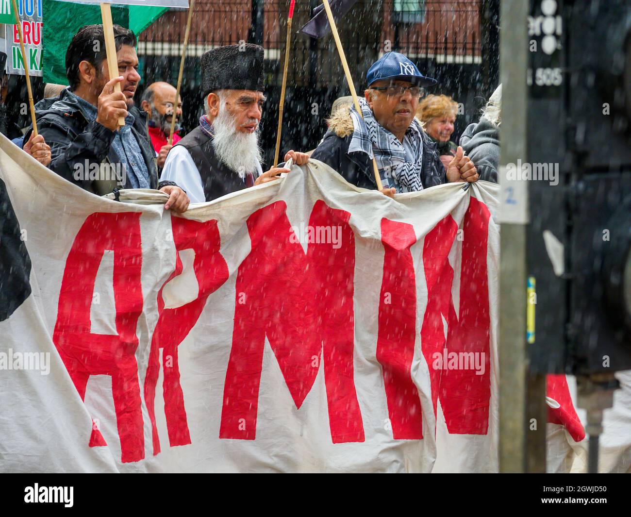 Manchester Muslim protest march at Tory party conference men holding banner in a heavy rain storm Stock Photo