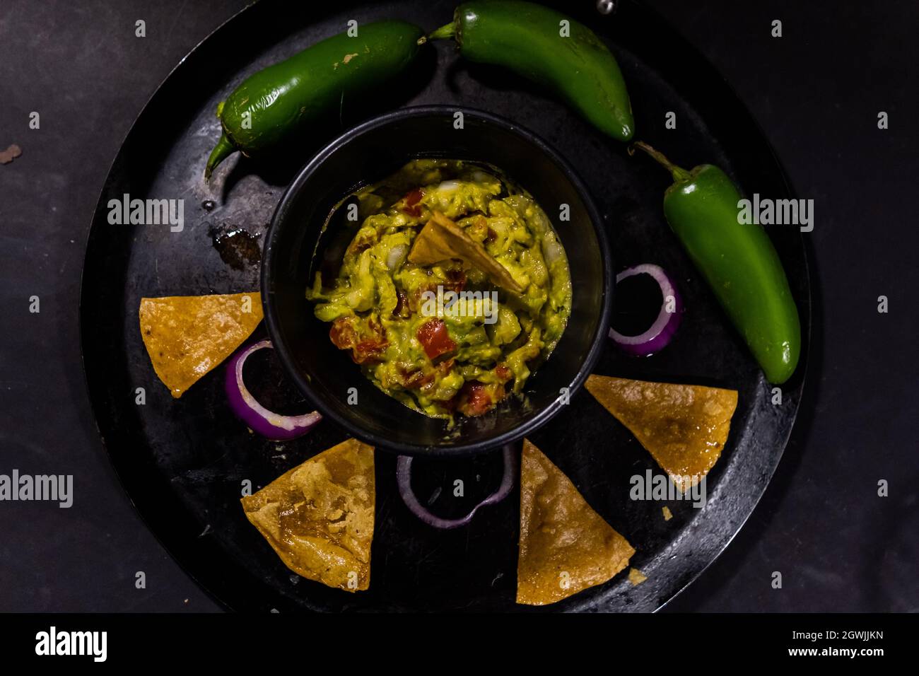 https://c8.alamy.com/comp/2GWJJKN/bowl-of-guacamole-on-mexican-comal-decorated-with-tortilla-chips-and-vegetables-2GWJJKN.jpg