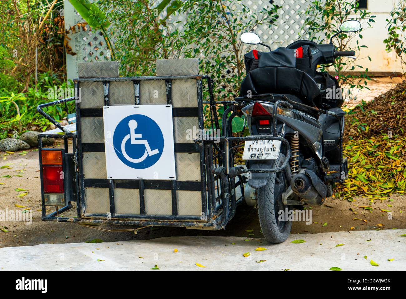 Scooter with a wheelchair trailer. Special adaptation of bikes in Asia. Samui , Tailand - 02.13.2020 Stock Photo