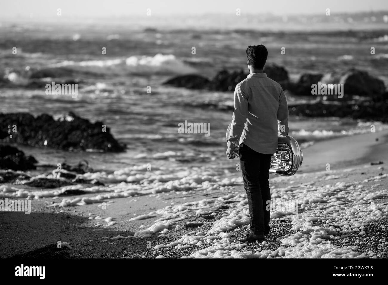 A musician man with a tuba on the seashore. Black and white photo. Stock Photo
