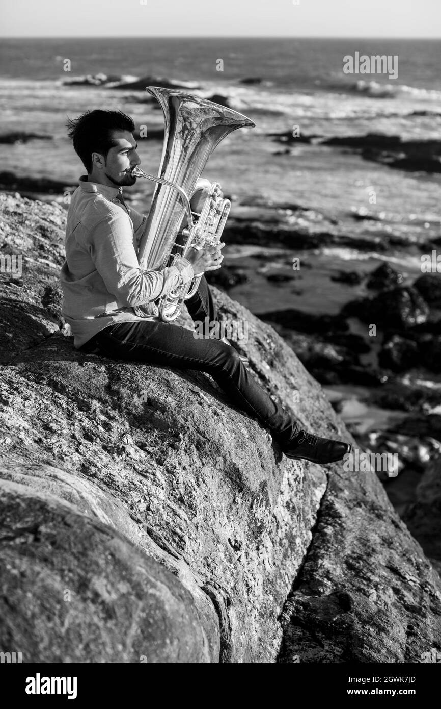 A musician man with a tuba on the sea coast. Black and white photo. Stock Photo