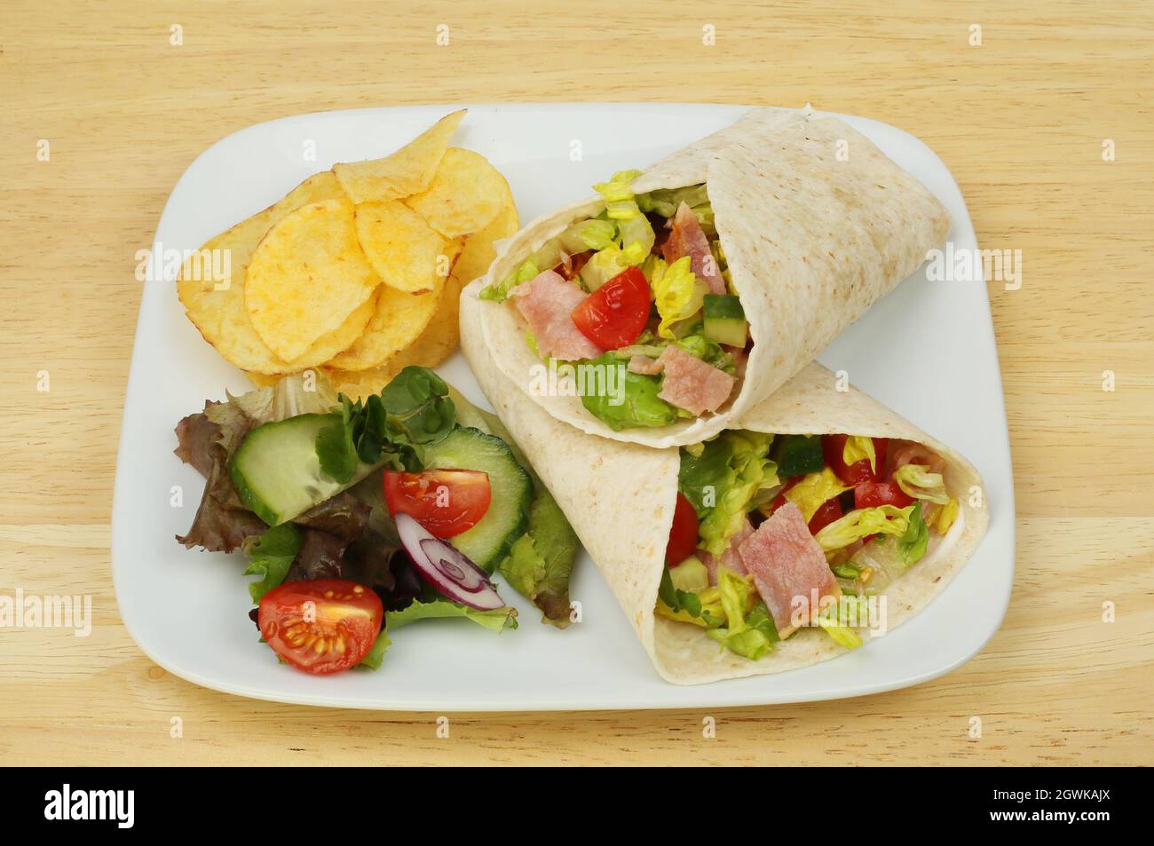 Bacon, lettuce and tomato wraps with salad and potato crisps on a plate