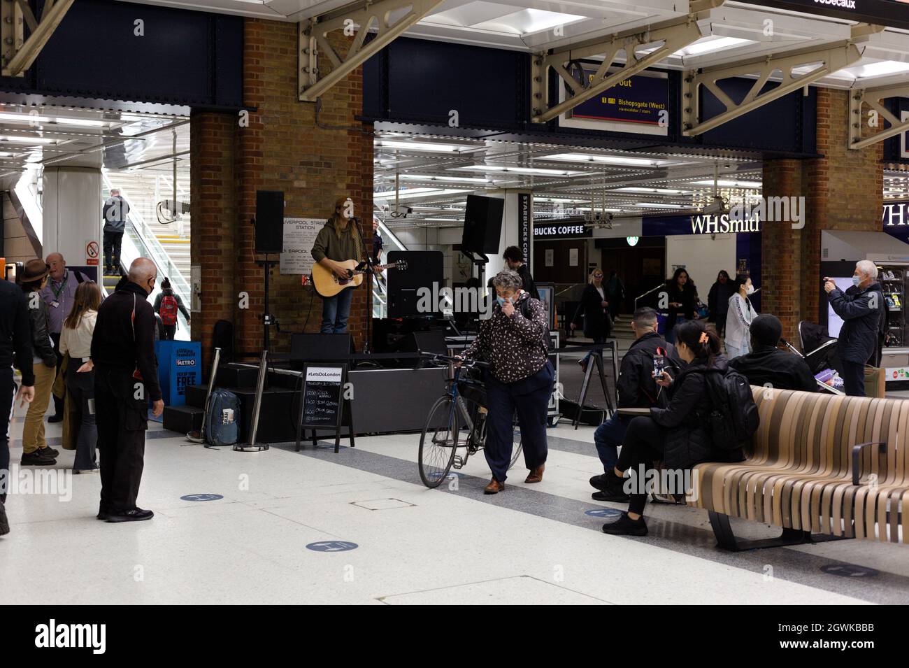 London, Britain. September 30th 2021.  Guitarist performing at Liverpool Street Rail Station as commuters watch capturing the performance on phone. Stock Photo