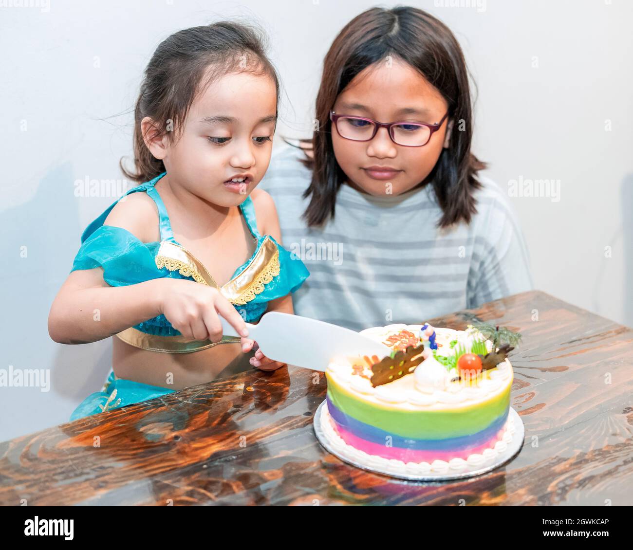 Little Girl Is Cutting Her Birthday Cake. Celebrating At Home With Family  During Quarantine Stock Photo - Alamy