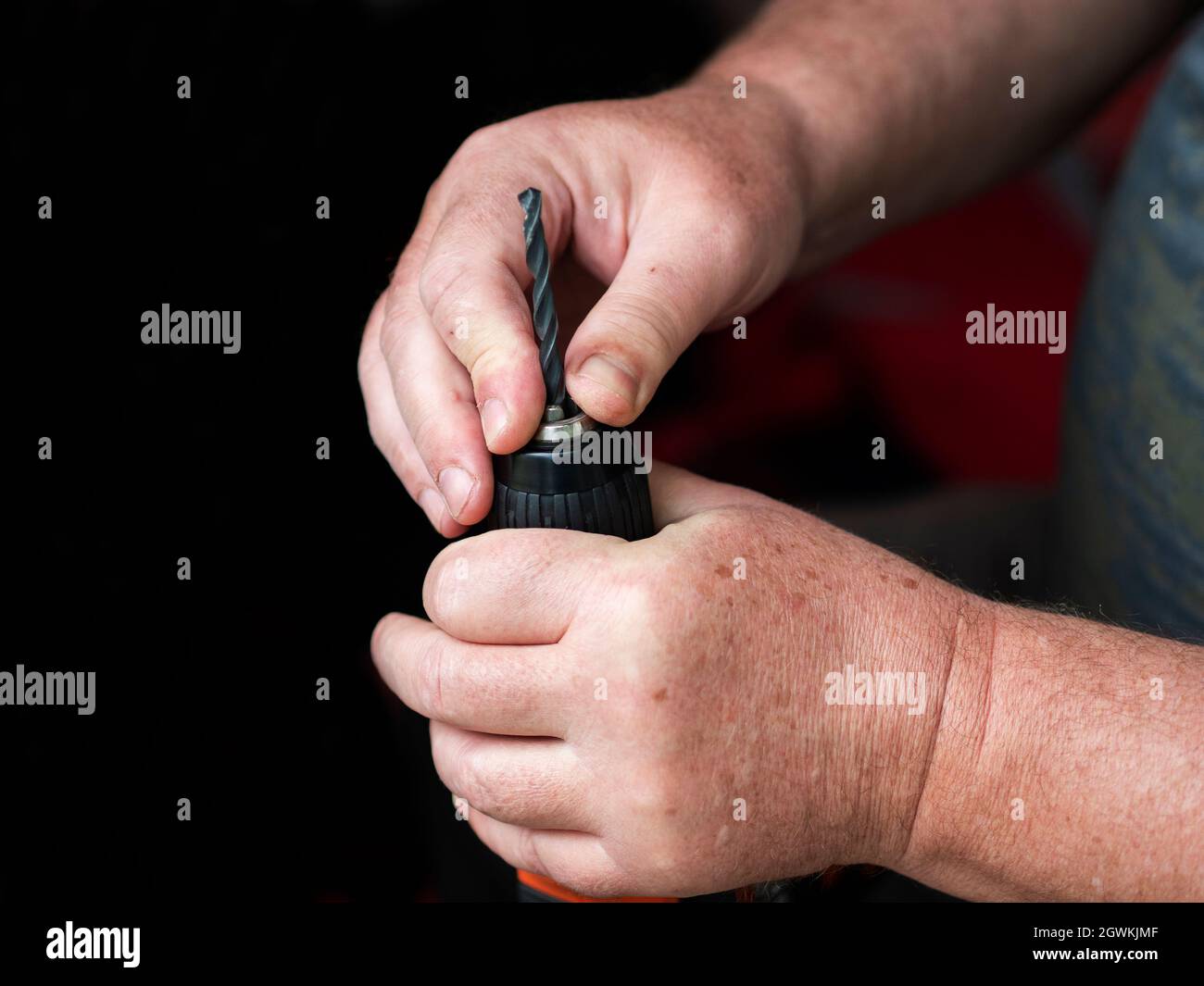 Hands Of A Caucasian Man Inserts A Drill Into An Electric Drill Chuck