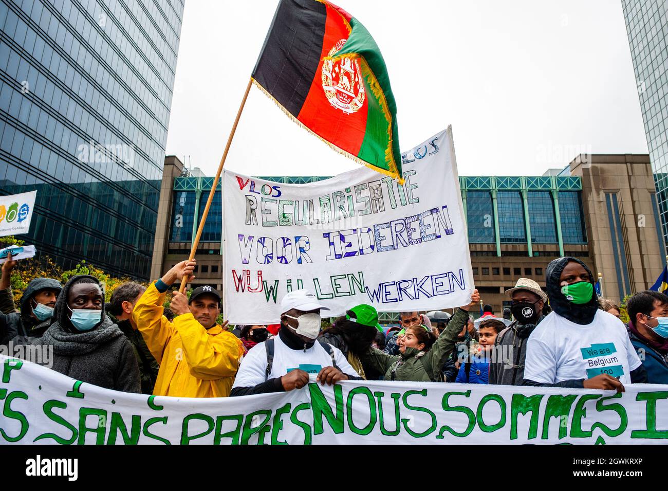 A man is seen holding a big Afghanistan flag close to a big placard asking for the regularization of the immigrants during the demonstration.Sans-papiers (without papers), an organization that represents and advocates for undocumented migrants in Belgium, planned a march in Brussels, as part of a broader campaign called “We are Belgium, too.” Thousands of people demonstrated to demand that a national regulatory commission should be established in regards to undocumented migration, and calls for the integration of undocumented migrants into the Belgian rule of law. Stock Photo