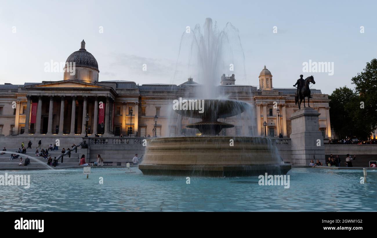 London, Greater London, England, September 21 2021: Fountain and National Gallery in Trafalgar Square at night with people relaxing in the steps. Stock Photo