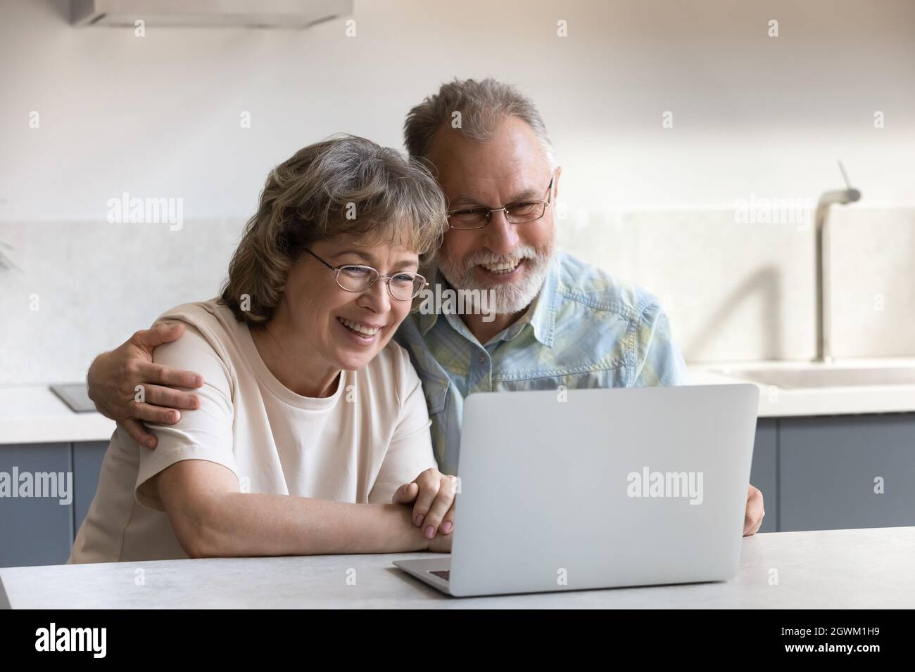 Happy bonding mature couple using computer at home. Stock Photo