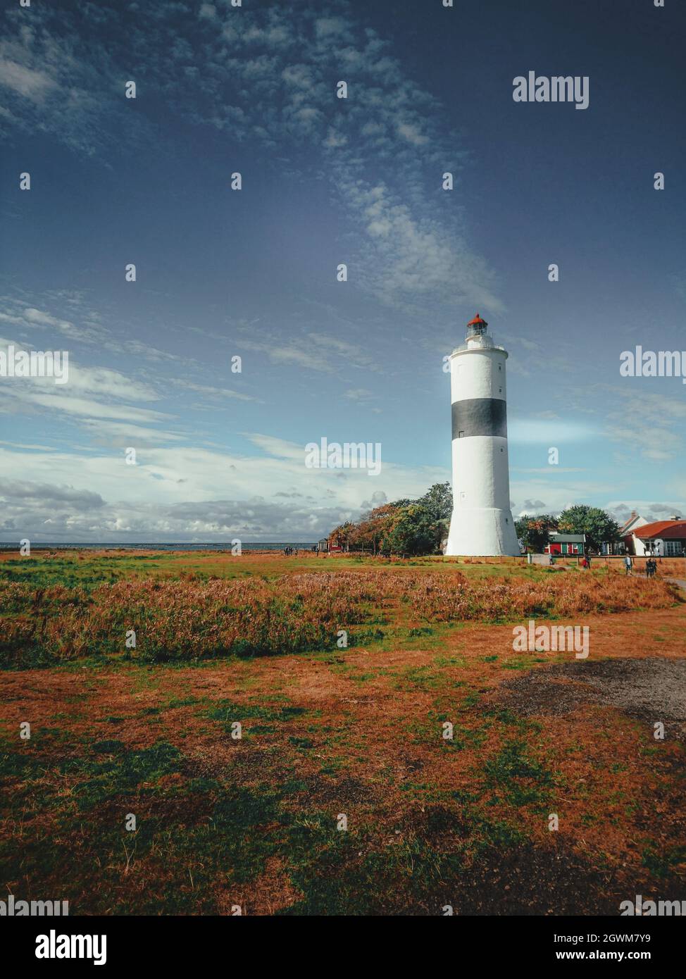 Lighthouse On Field By Building Against Sky Stock Photo