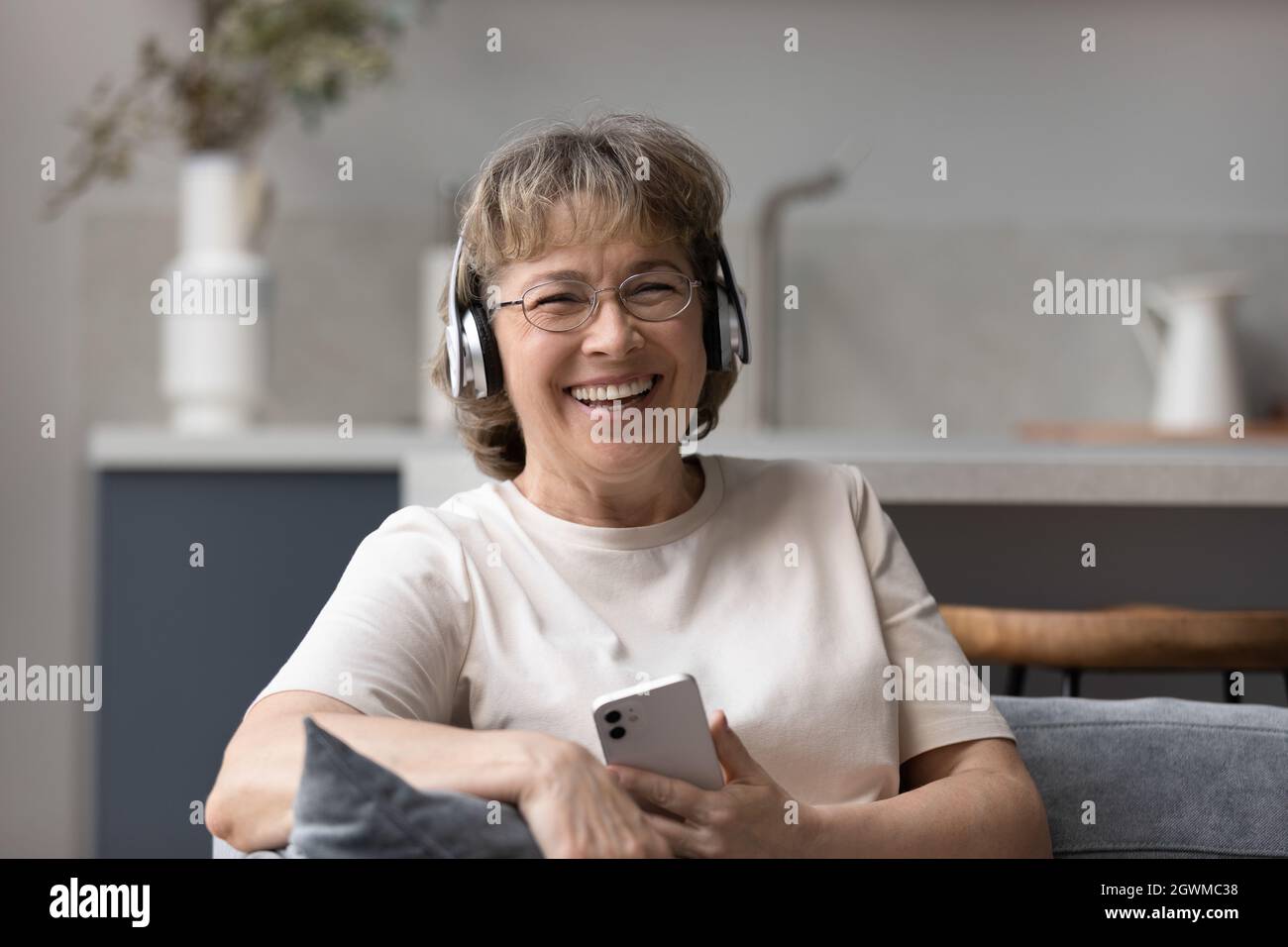 Happy laughing middle aged woman listening music in headphones Stock ...