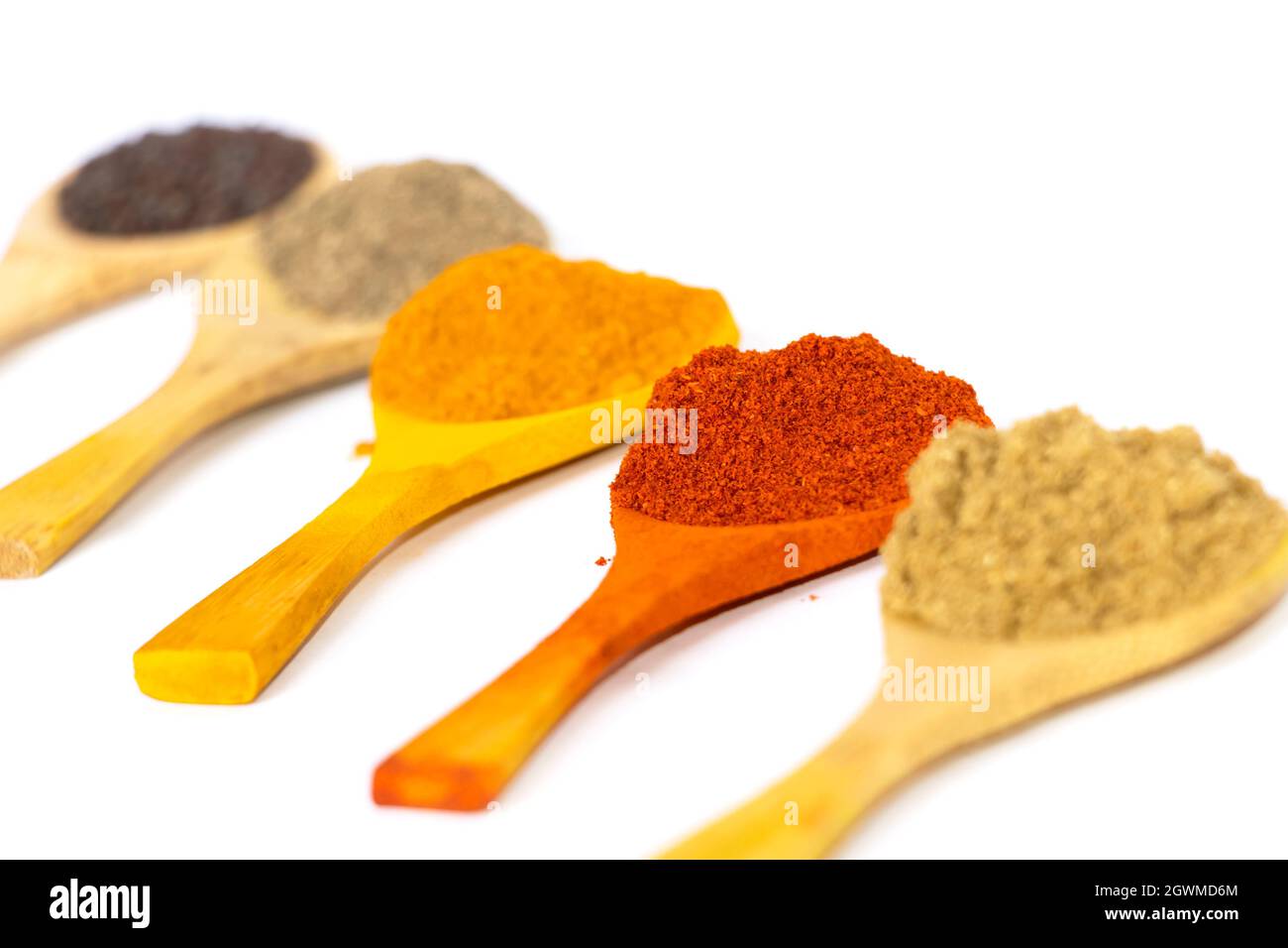Closeup Image Of Indian Curry Powders In Wooden Spoon. White Background. Selective Focus Stock Photo