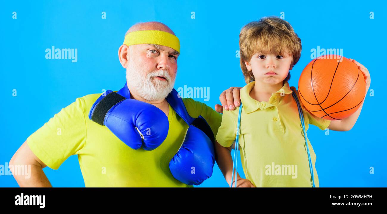 Grandfather and Grandchild sporting. Grandson with Basketball ball and Grandpa with boxing gloves. Family sport. Stock Photo