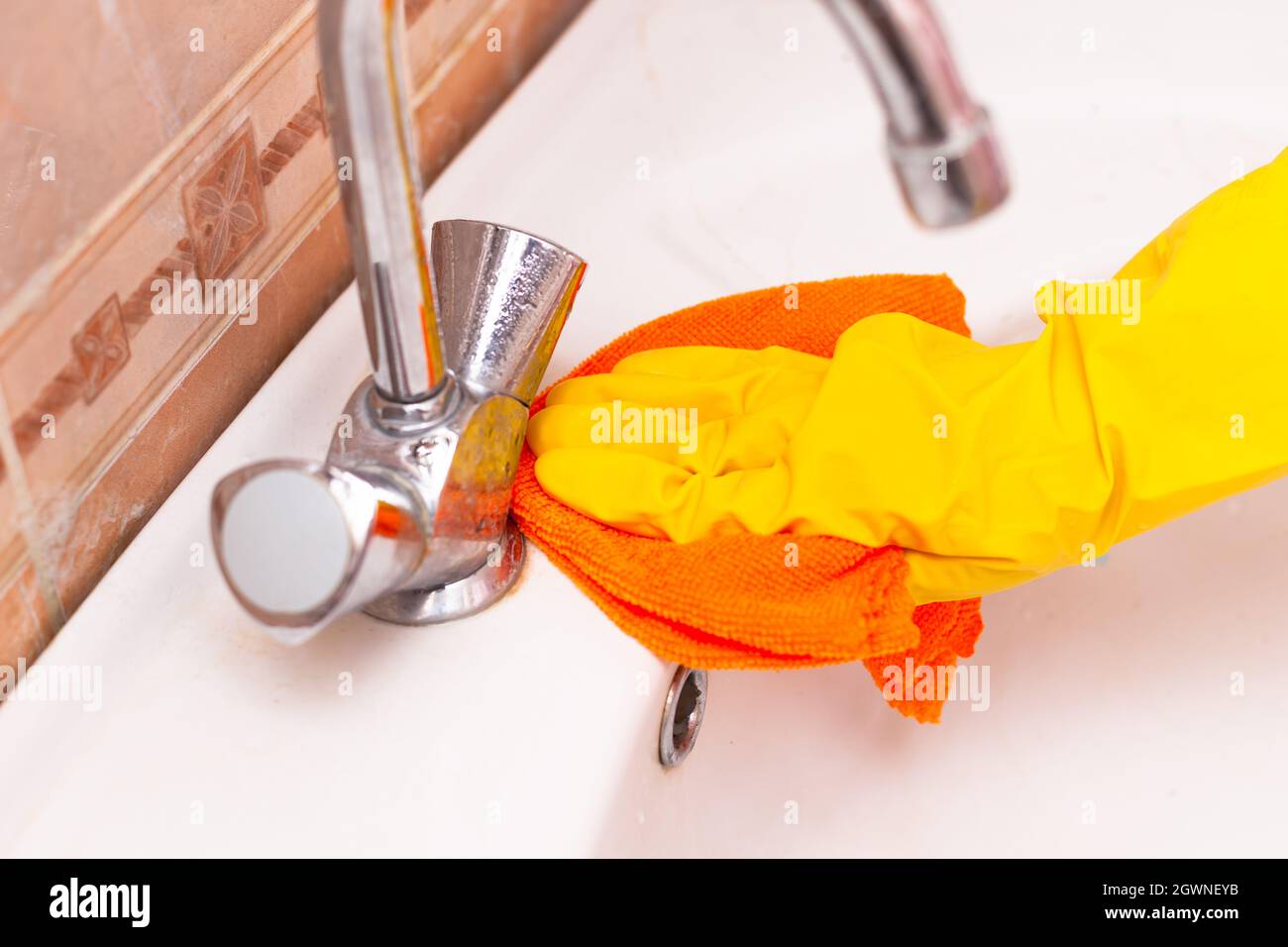 hand in a yellow rubber glove wipes the sink in the bathroom Stock ...