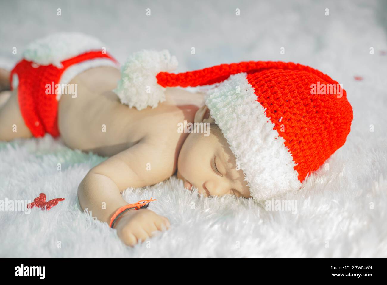Close Up Of A Baby Boy Sleeping On Bed In A Santa Hat Stock Photo