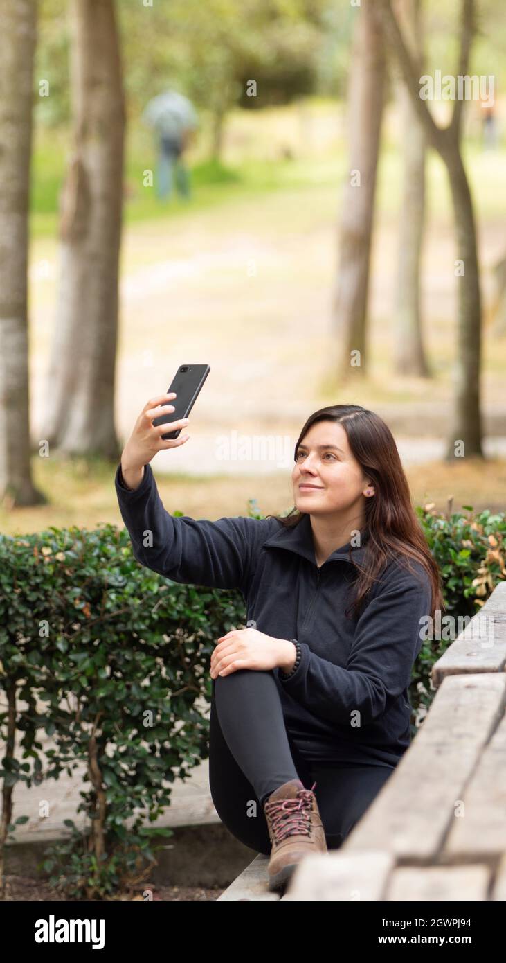 Beautiful young Hispanic woman taking a selfie with her cell phone ...
