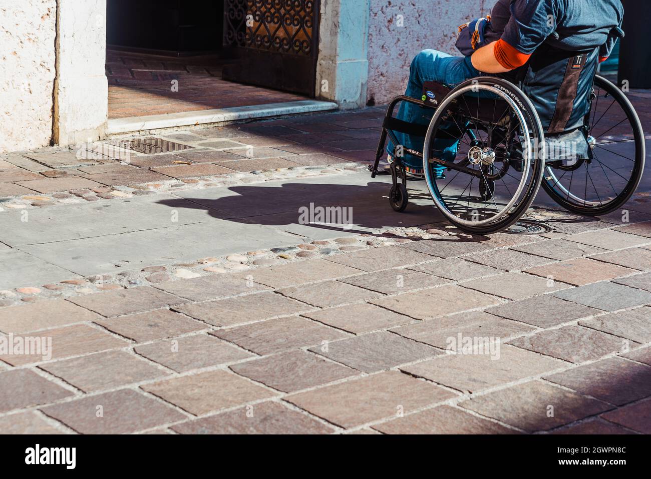 Rome, italy - september 22, 2021: A person in a wheelchair faces a step at the entrance of an unadapted building. Stock Photo