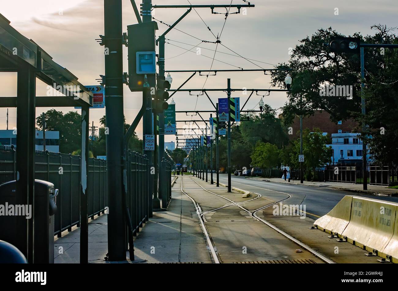 A New Orleans streetcar stop on the Canal Street Line shows the metal tracks the streetcars travel upon and the electric wire above that powers them. Stock Photo