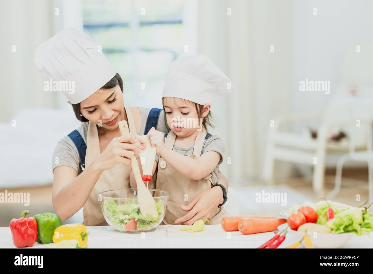 Happy Family Mom Teaching Cute Girl Preparing And Cooking Healthy Salad For The First Time. Stock Photo